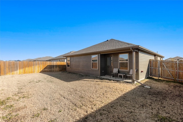 back of property featuring a fenced backyard, a shingled roof, and a patio