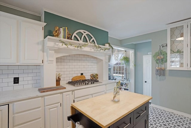 kitchen featuring stainless steel gas cooktop, ornamental molding, butcher block counters, and white cabinets