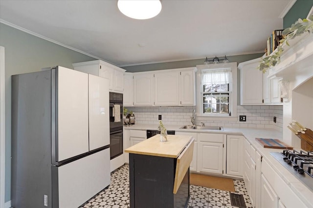 kitchen with black appliances, crown molding, butcher block countertops, and light floors