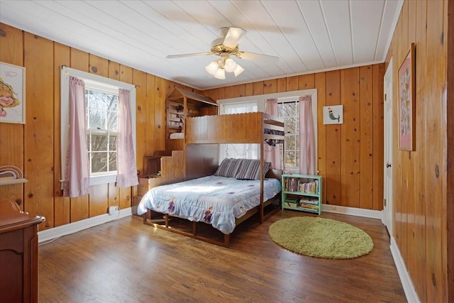 bedroom featuring wooden walls, wood finished floors, and baseboards