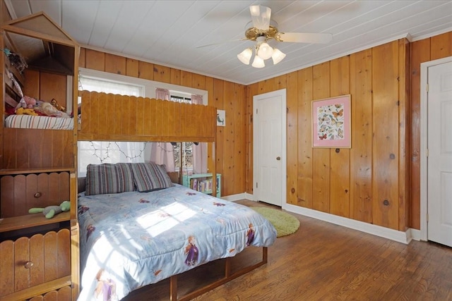 bedroom with wood walls, baseboards, and wood finished floors