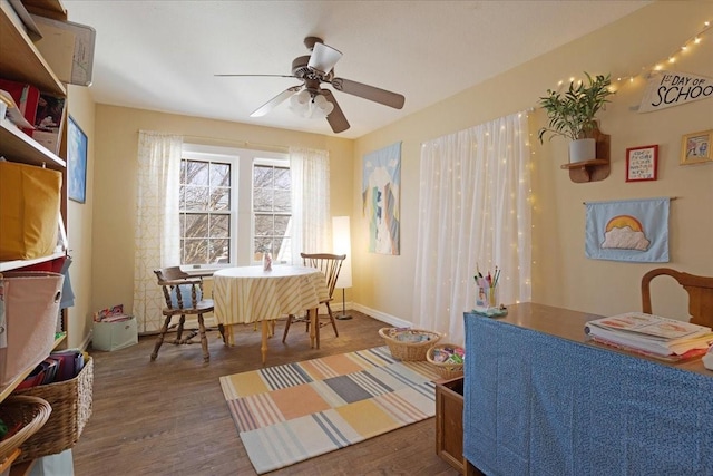 dining area with a ceiling fan, baseboards, and wood finished floors