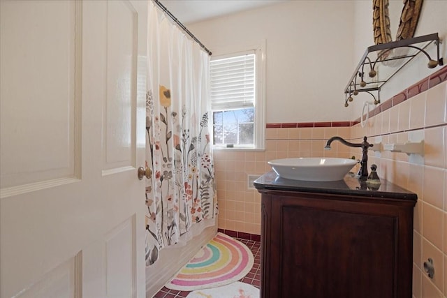 bathroom with a wainscoted wall, shower / tub combo, vanity, tile walls, and tile patterned floors