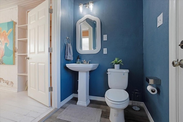 half bathroom featuring wood finished floors, toilet, and baseboards