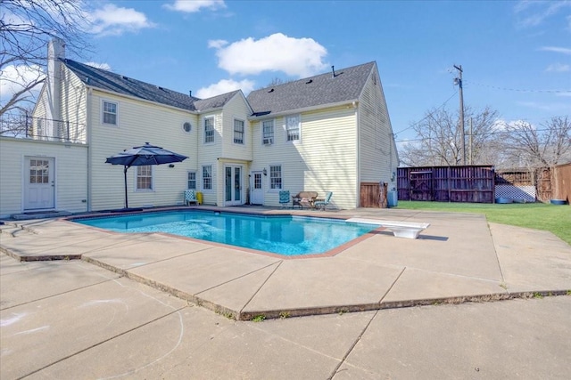 view of swimming pool featuring a diving board, a patio, fence, and a fenced in pool