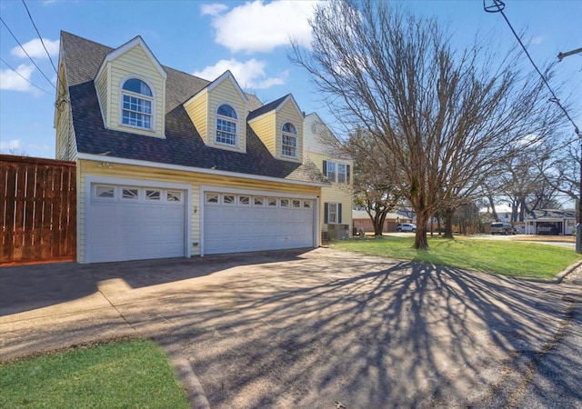 view of front of property with a shingled roof, a front yard, fence, a garage, and driveway