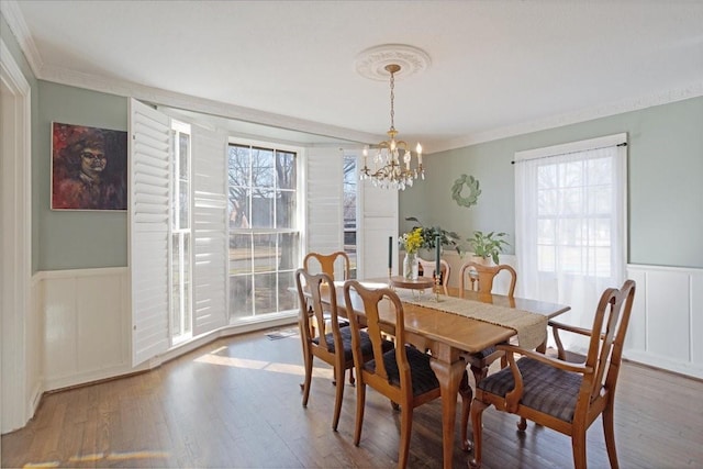 dining room with crown molding, wood finished floors, and wainscoting