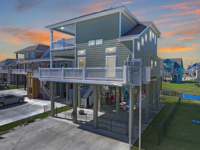 rear view of property with fence private yard, a balcony, stairway, a gate, and a carport