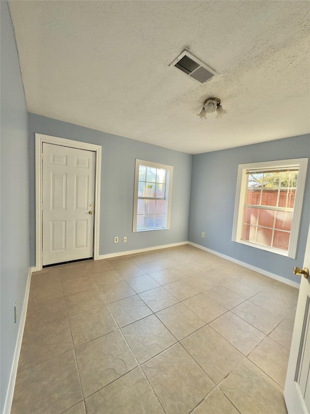 empty room featuring tile patterned flooring, visible vents, and baseboards