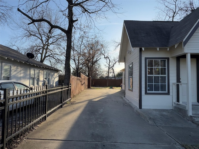 view of side of home with a shingled roof and fence private yard