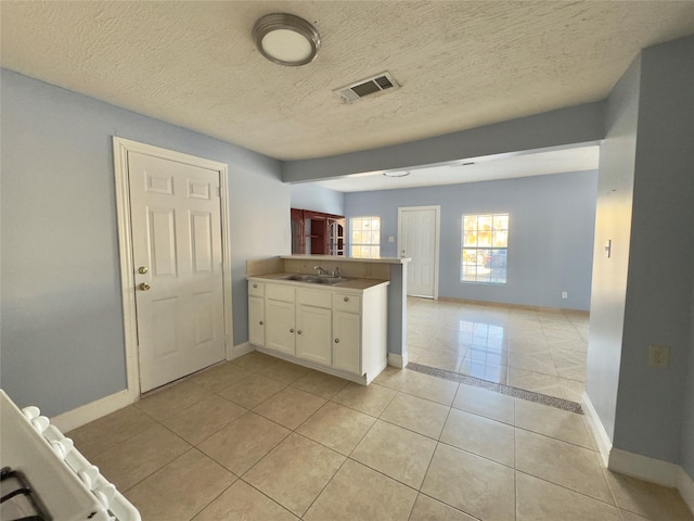 kitchen with white cabinets, visible vents, a peninsula, and baseboards