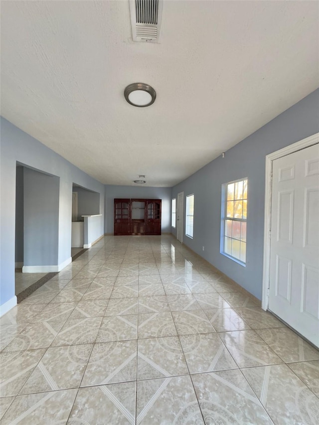 unfurnished living room featuring marble finish floor, baseboards, visible vents, and a textured ceiling