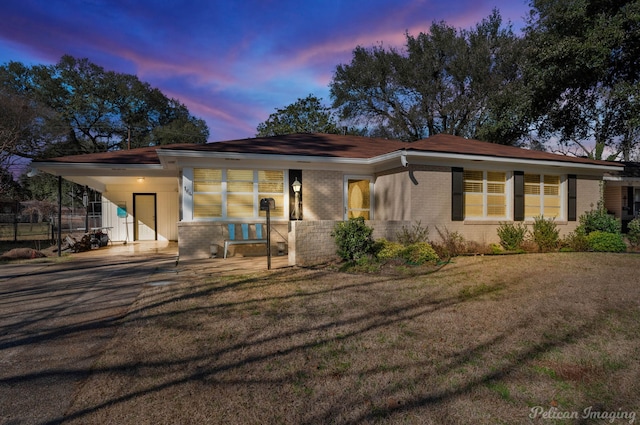 view of front facade featuring an attached carport, brick siding, and a front lawn