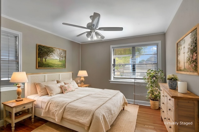 bedroom with a ceiling fan, crown molding, and light wood-style flooring