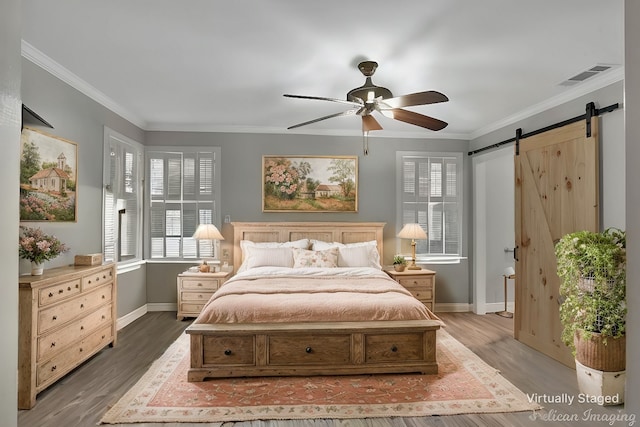 bedroom with ornamental molding, visible vents, and a barn door