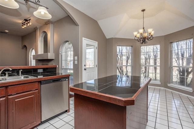 kitchen featuring light tile patterned floors, dishwasher, lofted ceiling, pendant lighting, and a sink