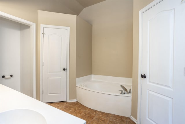 full bathroom featuring lofted ceiling, a garden tub, and a sink