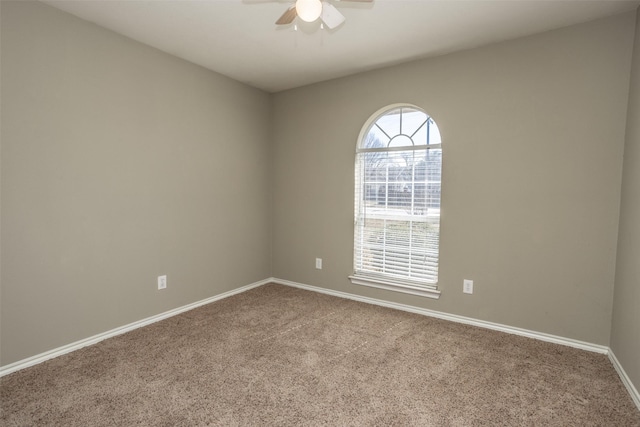 carpeted spare room featuring a ceiling fan and baseboards