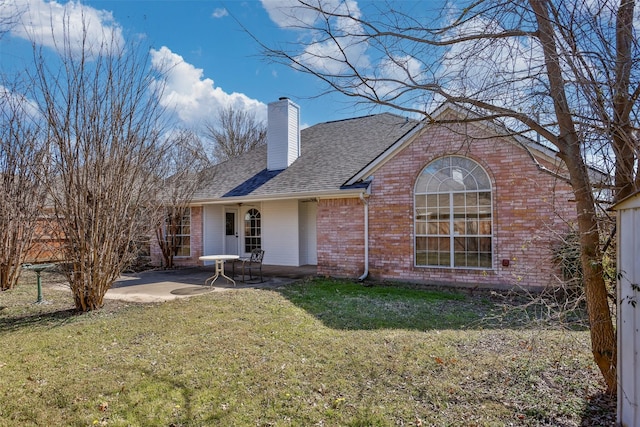 back of property featuring a shingled roof, a lawn, a patio, a chimney, and brick siding