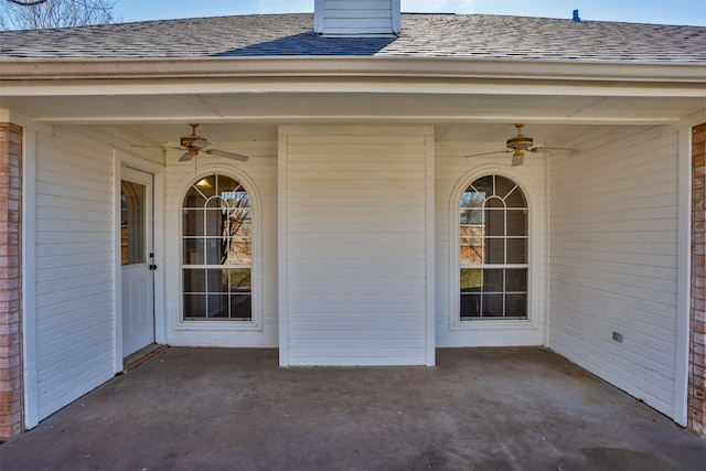 doorway to property with a patio, roof with shingles, and a ceiling fan