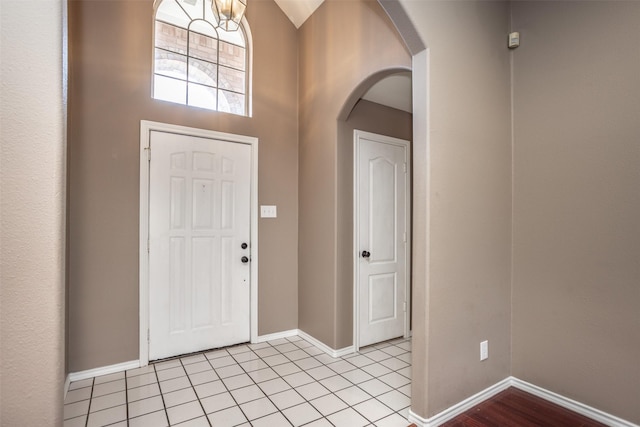 entrance foyer featuring arched walkways, light tile patterned floors, and baseboards