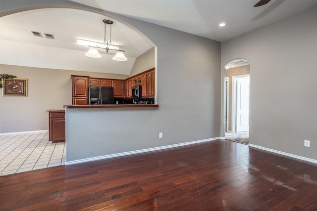 kitchen with decorative light fixtures, wood-type flooring, stainless steel microwave, baseboards, and black fridge