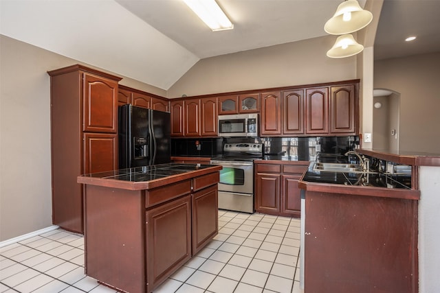 kitchen featuring light tile patterned floors, lofted ceiling, decorative backsplash, appliances with stainless steel finishes, and a sink