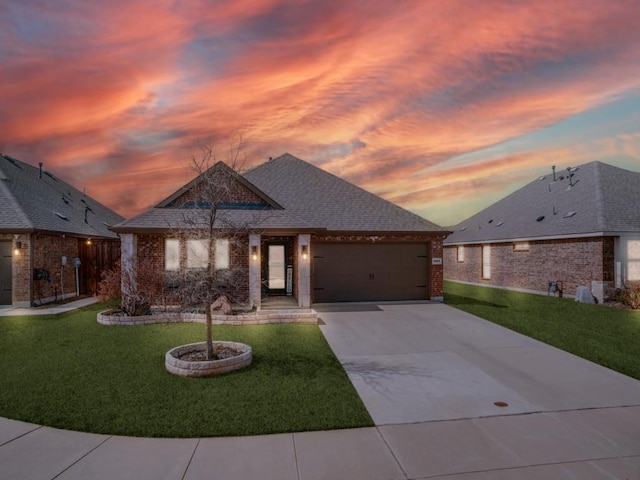 view of front of property with roof with shingles, brick siding, concrete driveway, a front yard, and a garage