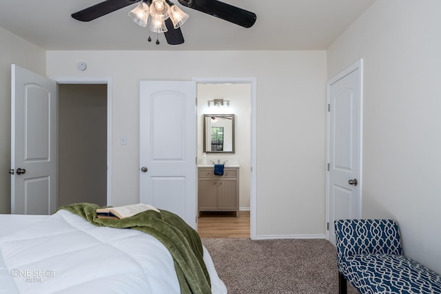 bedroom with ceiling fan, baseboards, ensuite bathroom, and light colored carpet