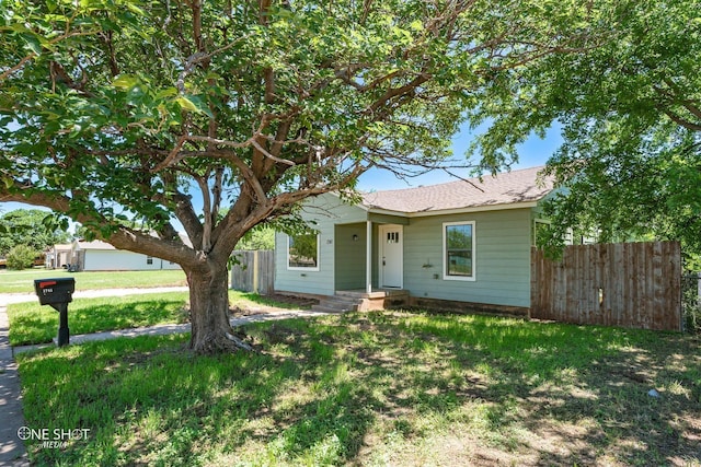 view of front of property featuring a shingled roof, fence, and a front yard