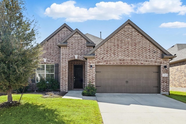 view of front of house featuring driveway, roof with shingles, a front yard, an attached garage, and brick siding