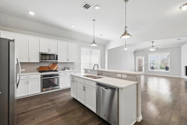 kitchen with decorative backsplash, a sink, appliances with stainless steel finishes, visible vents, and dark wood finished floors