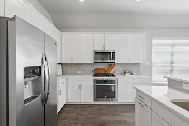 kitchen with stainless steel appliances, decorative backsplash, light countertops, white cabinets, and dark wood-type flooring