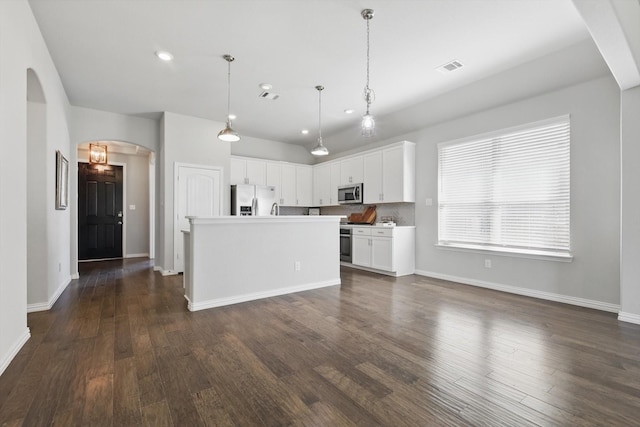 kitchen with visible vents, dark wood finished floors, stainless steel appliances, arched walkways, and white cabinetry