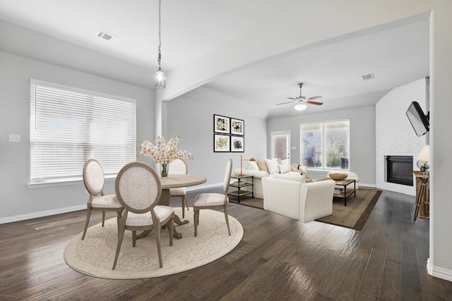 dining area with dark wood-style floors, visible vents, baseboards, and a fireplace