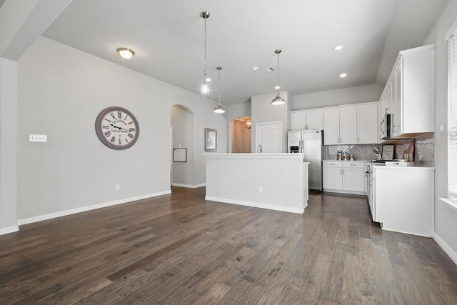 kitchen with arched walkways, decorative backsplash, stainless steel appliances, and dark wood-type flooring