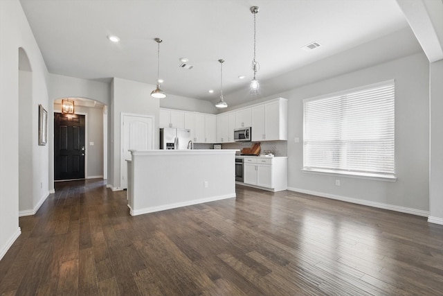 kitchen featuring white cabinetry, appliances with stainless steel finishes, visible vents, dark wood-style floors, and arched walkways