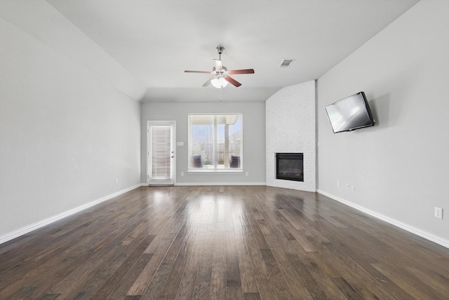 unfurnished living room featuring a brick fireplace, dark wood-type flooring, a ceiling fan, visible vents, and baseboards