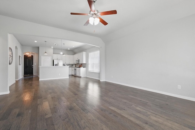 unfurnished living room featuring arched walkways, dark wood finished floors, baseboards, and a ceiling fan