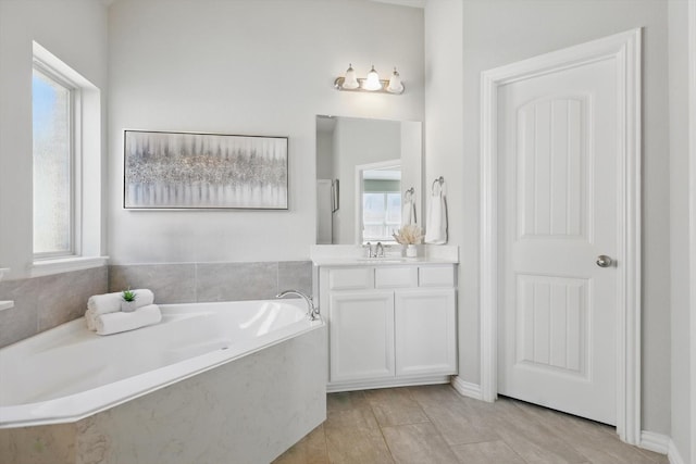 full bathroom with a healthy amount of sunlight, vanity, and a garden tub