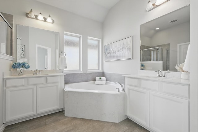 full bathroom featuring visible vents, a stall shower, two vanities, and a sink