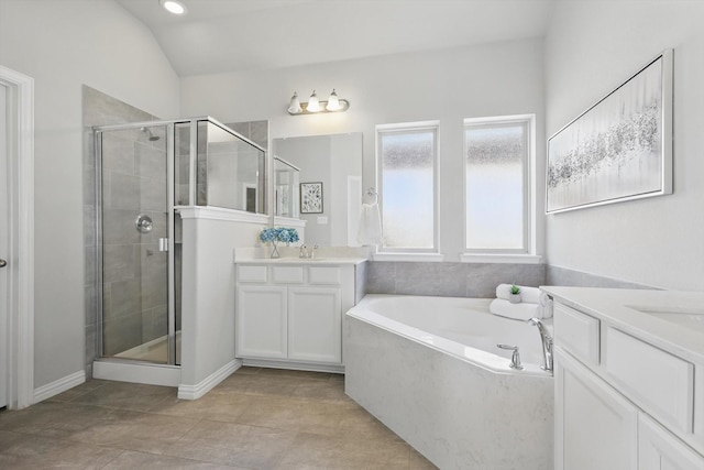 full bath with a garden tub, two vanities, a sink, a shower stall, and vaulted ceiling