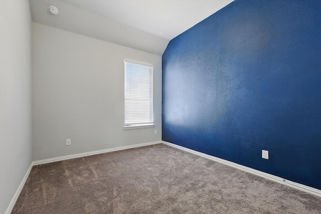 unfurnished room with baseboards, lofted ceiling, and carpet