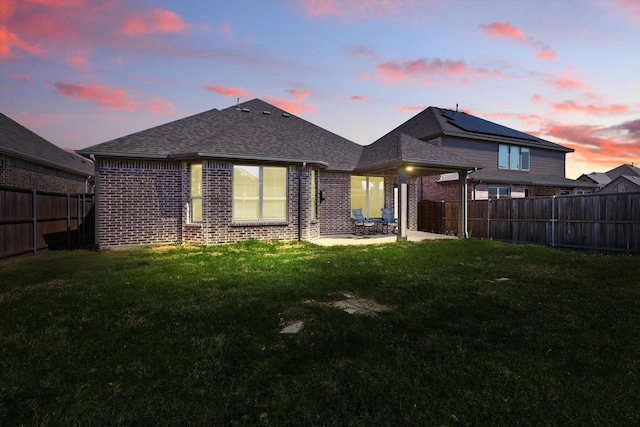 rear view of house featuring a patio, brick siding, a fenced backyard, and a yard
