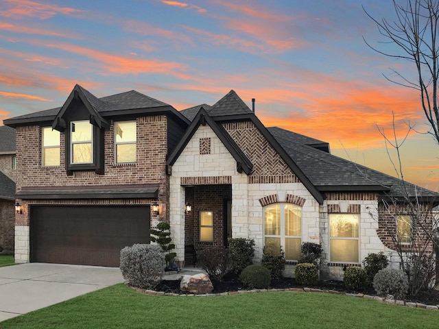 french country home featuring stone siding, roof with shingles, concrete driveway, and brick siding