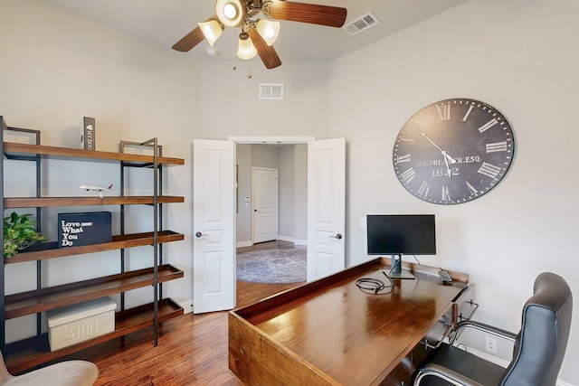 home office featuring a ceiling fan, visible vents, baseboards, and wood finished floors