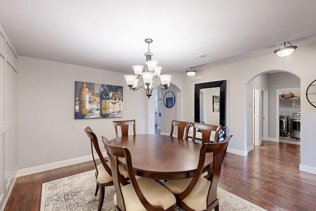 dining space with arched walkways, visible vents, independent washer and dryer, and wood finished floors