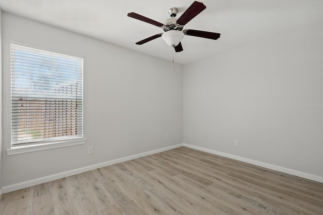 spare room featuring ceiling fan, light wood finished floors, and baseboards