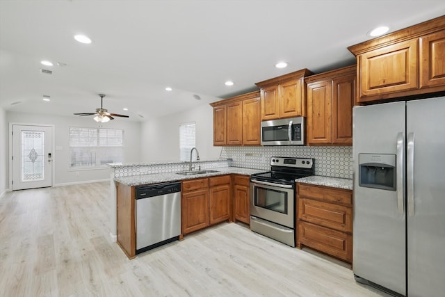 kitchen with stainless steel appliances, brown cabinets, a sink, and decorative backsplash