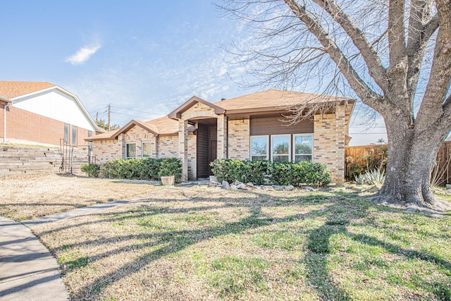 view of front of property with brick siding, fence, and a front lawn